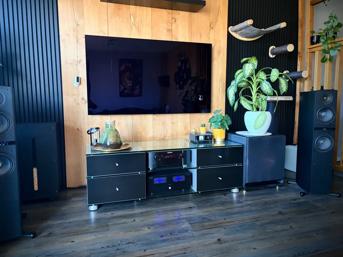 Home cinema setup met vloerstaande luidsprekers, AV-versterker en tv aan houten wand